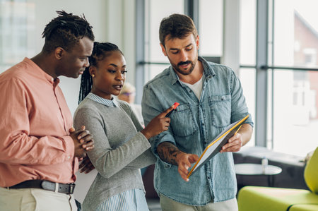 Three diverse business team discussing and planning projects using analytical papers during a meeting in the office. Business and finance concept. Multiracial business colleagues checking documents.の写真素材