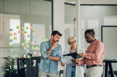 Three diverse business team discussing and planning projects using analytical papers during a...