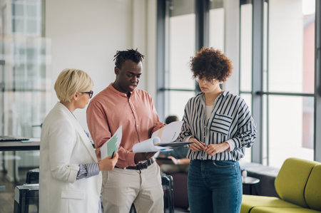 Three diverse business team discussing and planning projects using analytical papers during a meeting in the office. Business and finance concept. Multiracial business colleagues checking documents.の写真素材