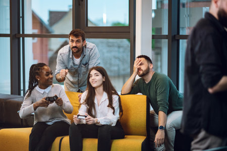 Multiracial coworkers playing video games in an office during a work break. Multiracial colleagues sitting in a coworking place in a friendly atmosphere.の写真素材