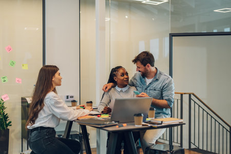 Three young multiracial businesspeople using a laptop while sitting in a boardroom. Diverse business colleagues having a discussion during a meeting.の写真素材