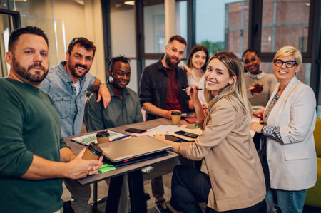 Cheerful diverse office people group talking and enjoying teamwork during staff meeting. Happy multiracial coworkers have fun working together at office brainstorming. Looking into the camera.の写真素材