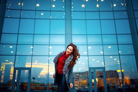 young beautiful girl in a gray raincoat red sweater black pants mess of the shopping centerの写真素材