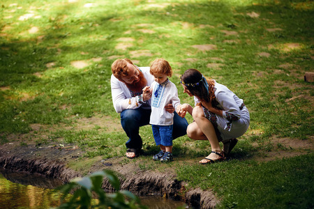 Happy ukrainian family with little son in traditional ukrainian dress in a countryside, parkの写真素材