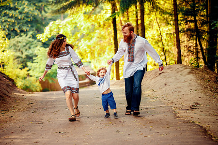 Happy ukrainian family with little son in traditional ukrainian dress in a countryside, parkの写真素材