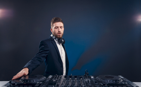 Man in dark  suit play music on a djs mixer. Studio shot.の写真素材