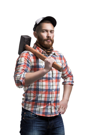 Redhead Bearded man wearing a baseball cap and shirt holding a hammer on a shoulder with an expression.の写真素材