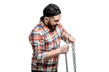 Redhead Bearded man wearing a baseball cap and shirt making strength against a chain.