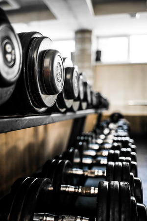 Sport Background. Rack of dumbbells in health club. Shelf with metal on gym studio room backdrop.の写真素材