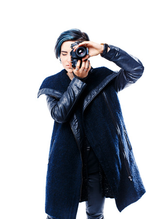Portrait of young girl in coat with hairstyle photographing with old film camera. Studio shotの写真素材