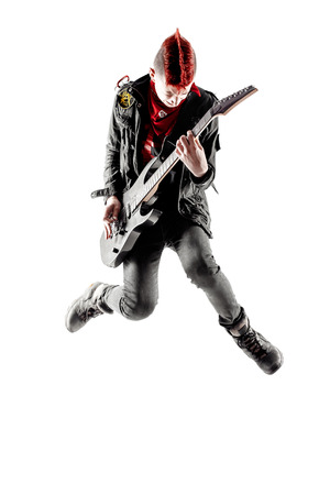 Wild teen boy with red haired mohawk playing guitar while jumping. Isolatedの写真素材