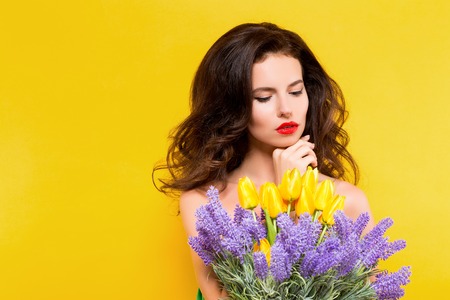 Portrait of attractive brunette in green dress with beautiful flowers on yellow background. Isolatedの写真素材