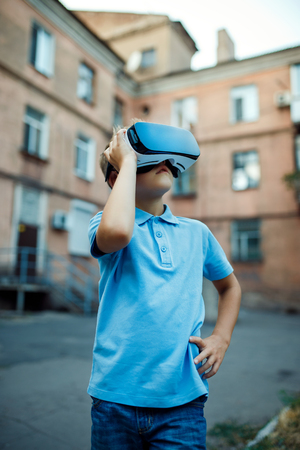 Fascinated little boy using VR virtual reality goggles. outdoorの写真素材