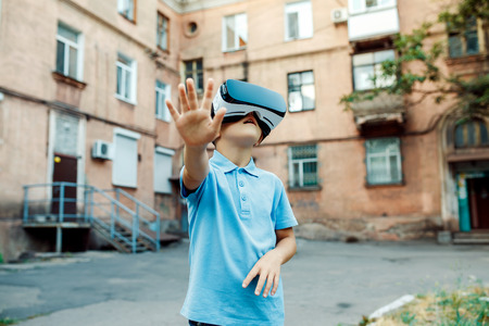 Fascinated little boy using VR virtual reality goggles. outdoor
