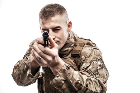 Young man wearing military uniform and aiming with handgun on white background.の写真素材