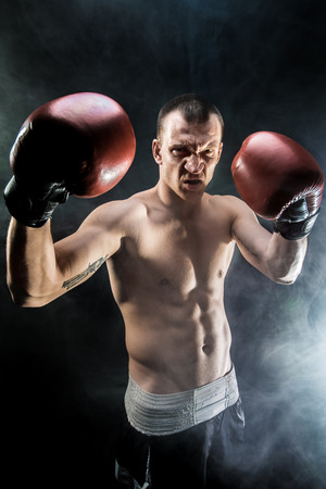 Muscular kickbox or muay thai fighter punching in smoke.の写真素材