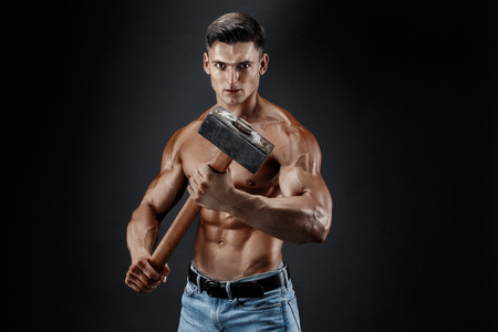Muscular man with naked torso holding big hummer. Isolated on dark grey backgroundの写真素材