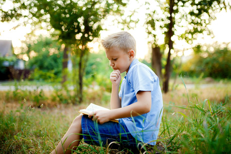 Kid sitting in the forest with book on the knees .の写真素材