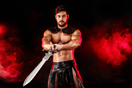 Severe barbarian in leather costume with sword in smokeの写真素材