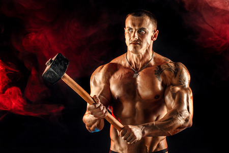 Portrait of serious muscular topless man with sledgehammerの写真素材
