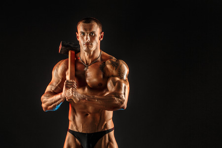 Portrait of serious muscular topless man with sledgehammerの写真素材