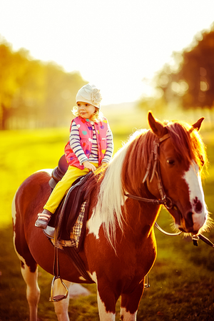 outdoors shot of cute little girl riding a chestnut equine.の写真素材