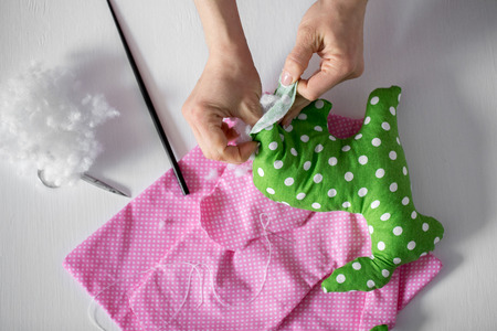 Hands of person stuffing a toy made with the green spotted textile.の写真素材