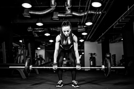 Muscular young fitness woman doing heavy deadlift exercise in gymの写真素材