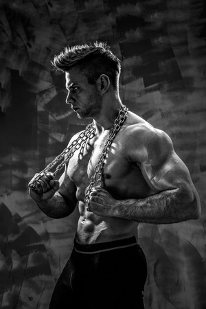 The Perfect male body - Awesome bodybuilder posing Holding a metal chainの写真素材
