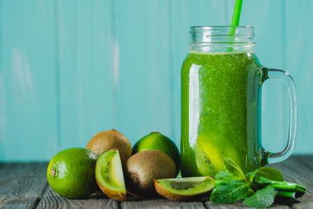 Blended green smoothie with ingredients on wooden table selective focus. Blue background.の写真素材