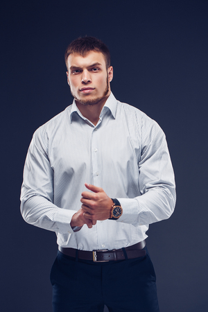 Fashion young man holding hand with watch on dark backgroundの写真素材