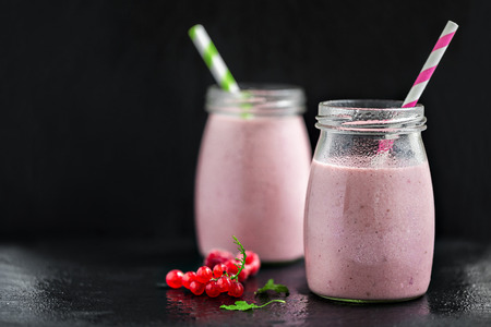 Two glasses with berry pink smoothies with currant and cranberry, selective focusの写真素材