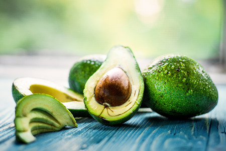 Fresh Green Avocado on blue wooden background.