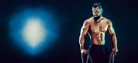 Muscular bearded bodybuilder man Posing with ropein studio.の写真素材