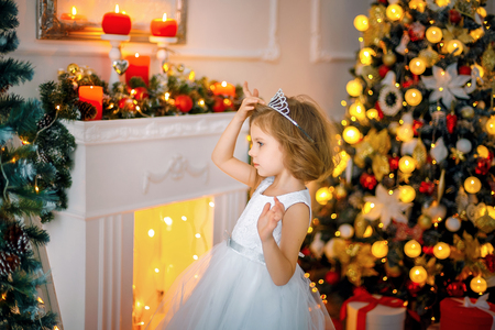 Little girl posing in a dress near the mirror whike adjusting crown on her head.の写真素材