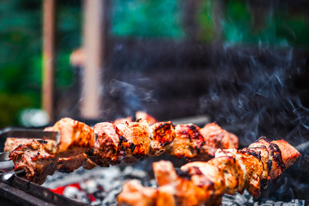 Grilled kebab cooking on metal skewer. Roasted meat cooked at barbecue. BBQ fresh beef meat chop slices. Traditional eastern dish, shish kebab. Grill on charcoal and flame, picnic, street foodの写真素材