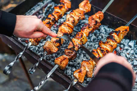 Grilled kebab cooking on metal skewer. Roasted meat cooked at barbecue. BBQ fresh beef meat chop slices. Traditional eastern dish, shish kebab. Grill on charcoal and flame, picnic, street foodの写真素材