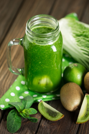 Blended green smoothie with ingredients on wooden table selective focusの写真素材