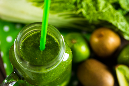 Blended green smoothie with ingredients on wooden table selective focusの写真素材