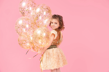 Adorable little girl with balloons looking at camera and smile on pink background.の写真素材