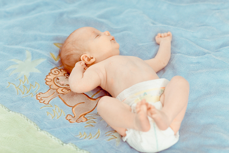 five months old lovely baby portrait. little boy in pampers lies on the bedの写真素材