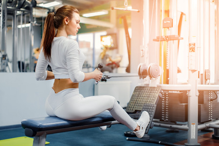 Young Woman training back with weight-lifting training machine