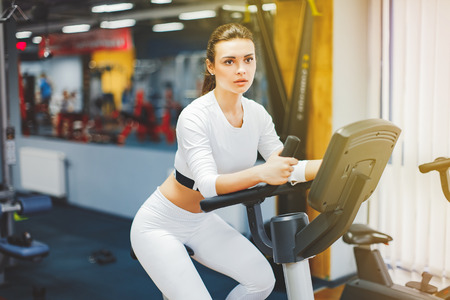Indoor cycling woman doing HIT cardio workout biking on indoors gym bike. Girl cyclist working out...