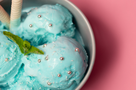 Pictachio ice cream with waffle sticks, several leaves of mint in bowl on pink background. copy space. gelatoの写真素材