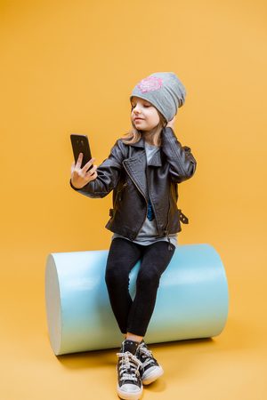 Cute pretty stylish girl in fashionable clothes taking selfie on yellow background.の写真素材