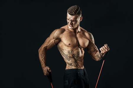 Handsome muscular strong man doing pulling exercise and working hard.の写真素材