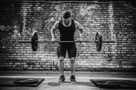 Muscular fitness man doing deadlift a barbell over his head in outdoor, street gym. Functional training. Snatch exerciseの写真素材