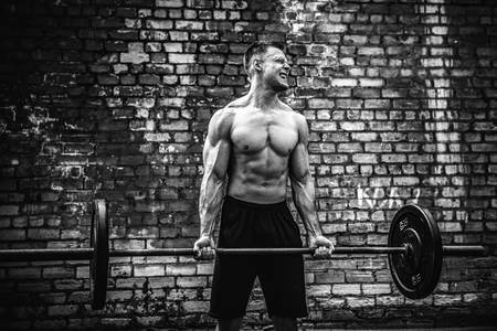 Muscular fitness man doing deadlift a barbell over his head in outdoor, street gym. Functional training. Snatch exerciseの写真素材