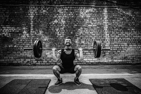 Muscular fitness man doing deadlift a barbell over his head in outdoor, street gym. Functional training. Snatch exerciseの写真素材
