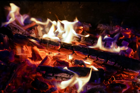Burning firewood in the fireplace close up, BBQ fire, charcoal background. Charcoal fire with sparks